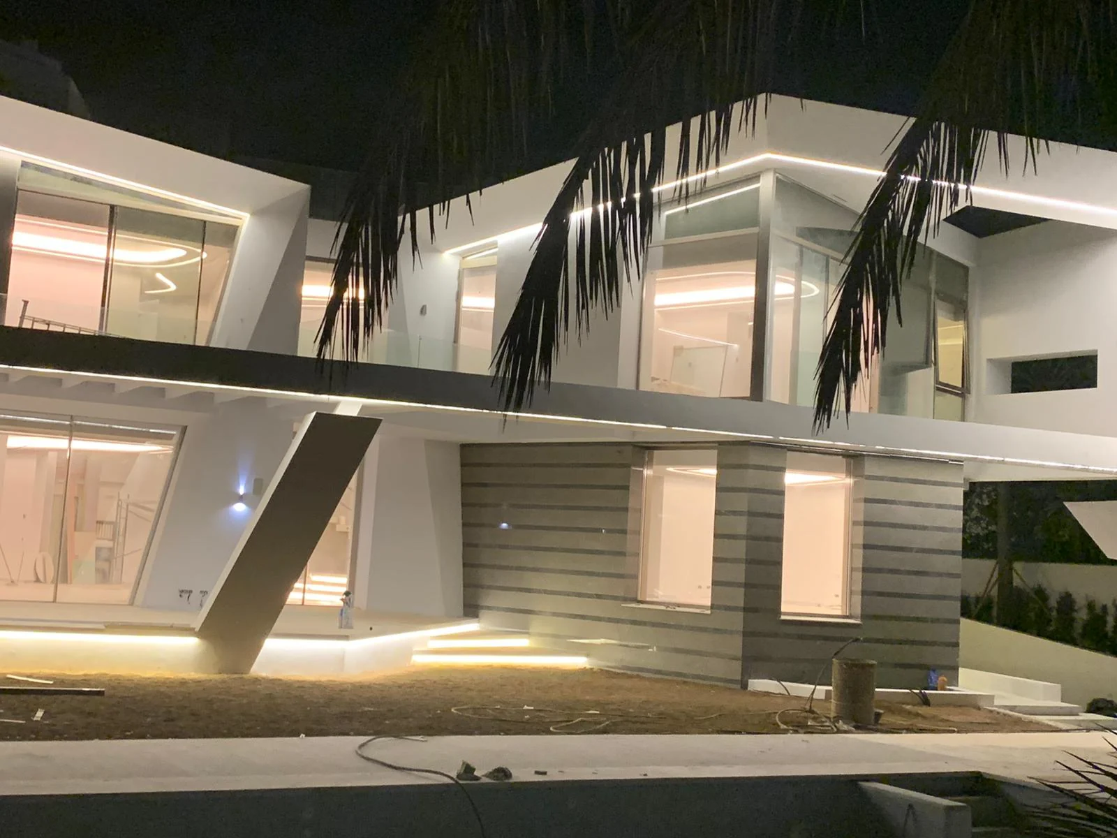 Iluminación nocturna de una vivienda contemporánea, con líneas de luz en su fachada.