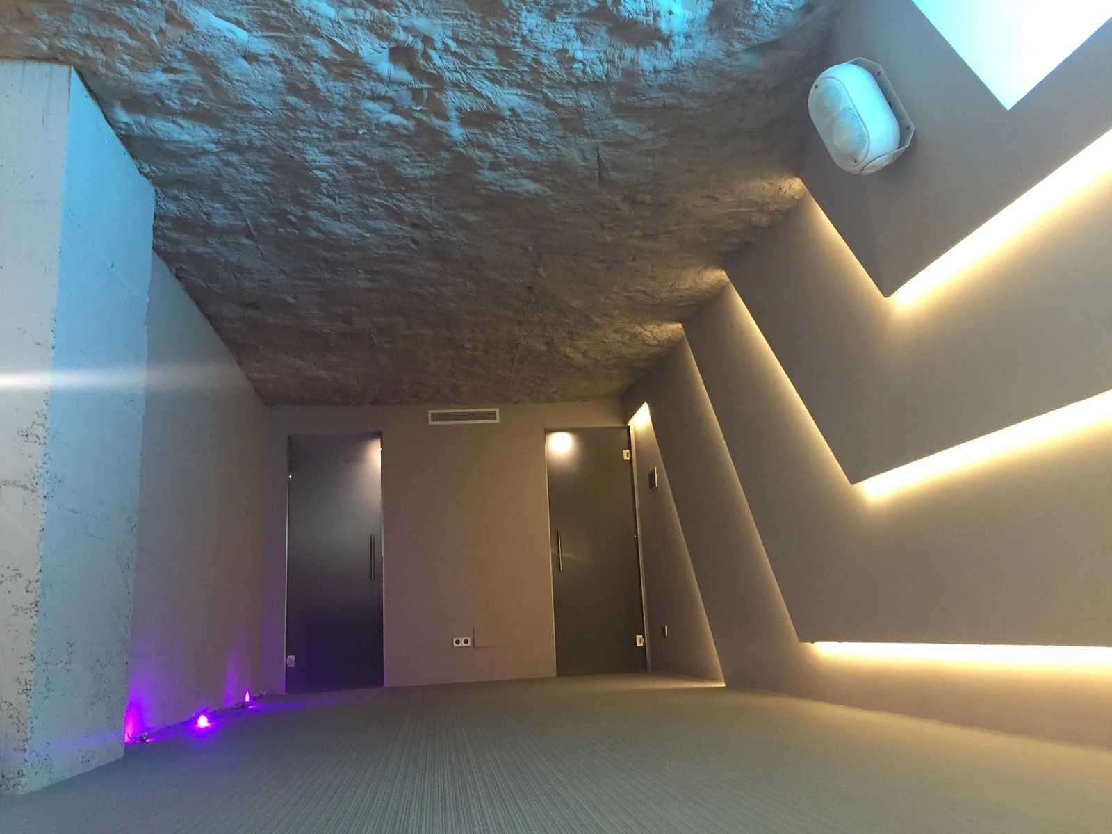 Iluminación lineal integrada en el techo de un espacio con paredes de piedra.